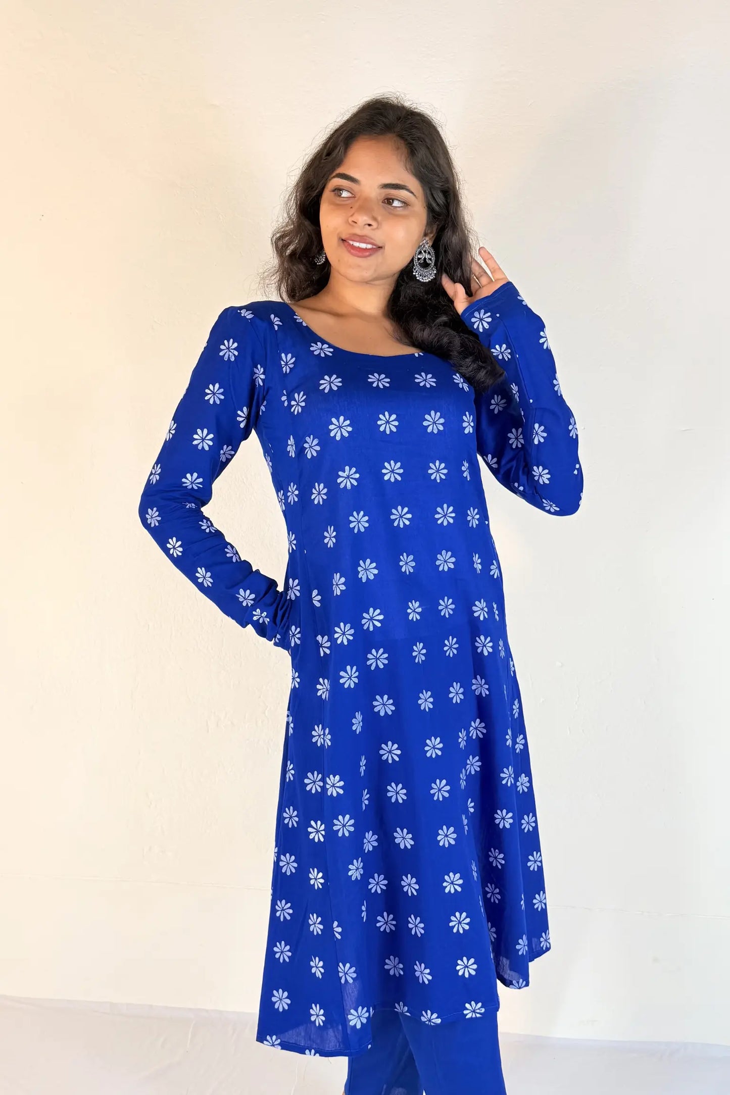 Woman wearing a blue kurta with white floral patterns against a plain background