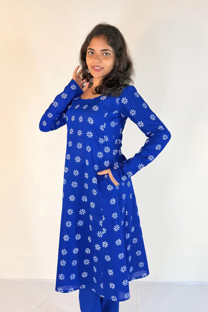 Woman wearing a blue dress with white floral patterns against a plain background