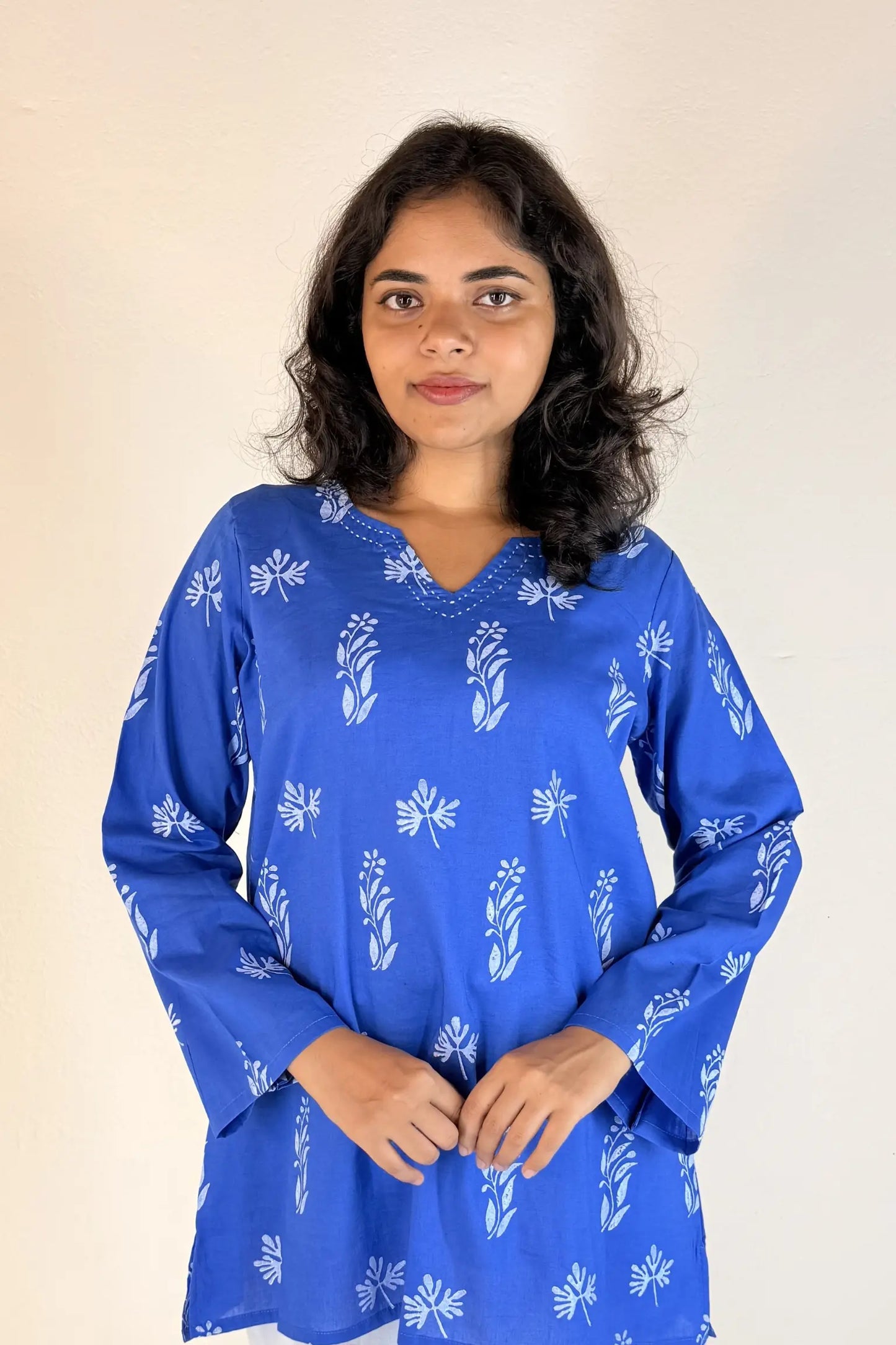 Woman wearing a blue patterned top against a beige background