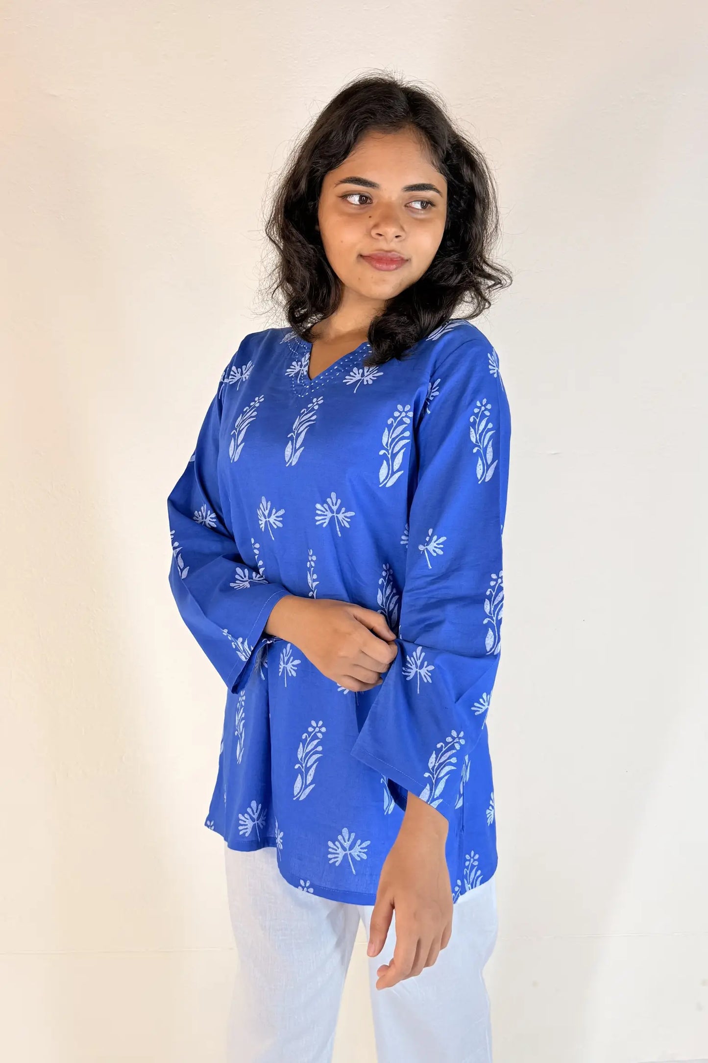 Woman wearing a blue printed top against a plain background