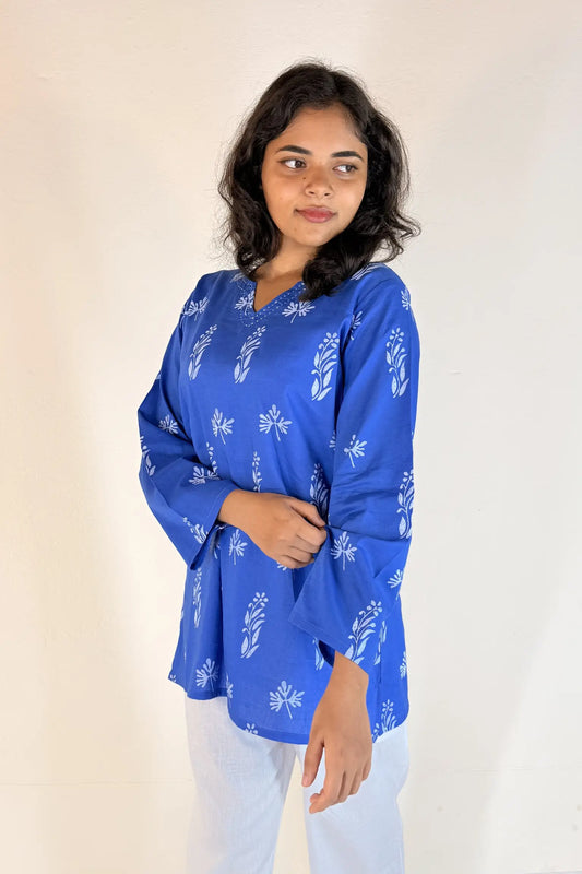 Woman wearing a blue printed top against a plain background