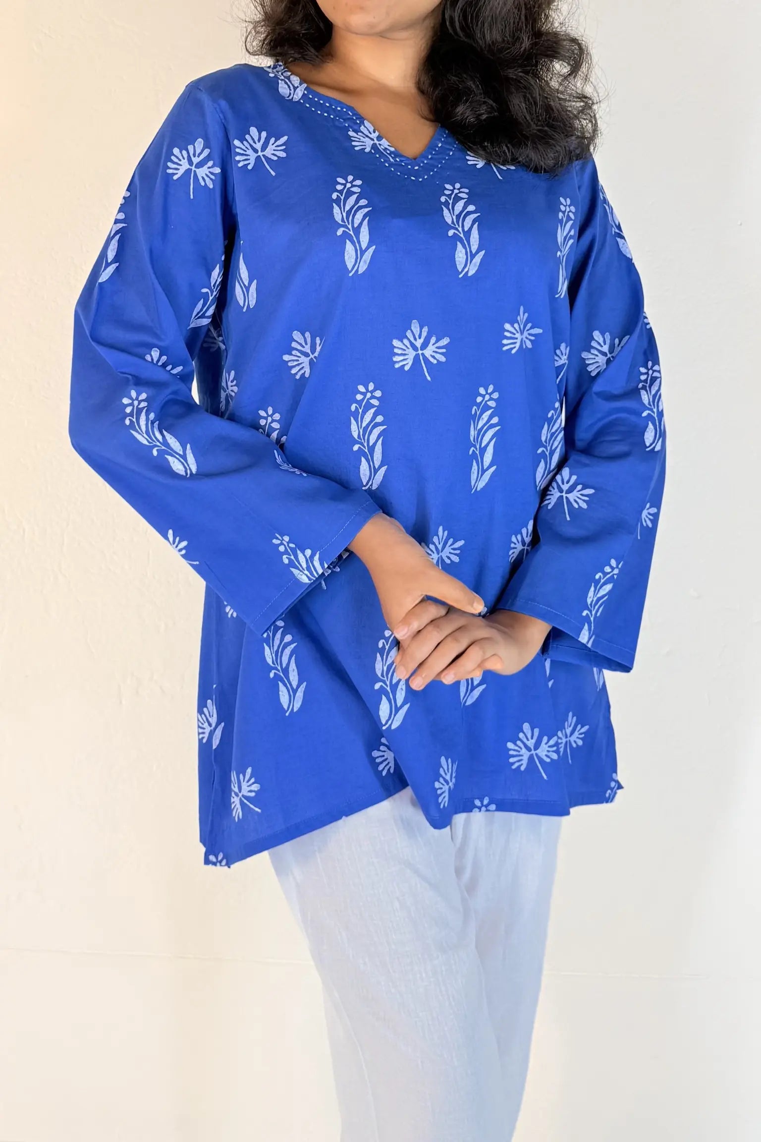 Woman wearing a blue floral patterned top against a plain background