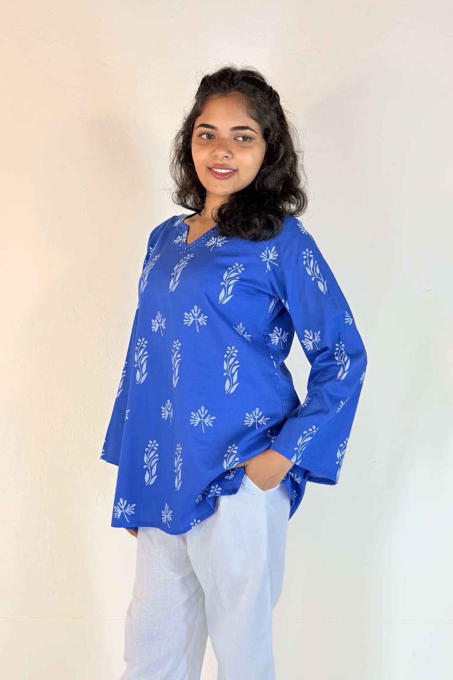 Woman wearing a blue patterned top against a plain background