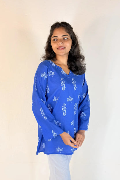 Woman wearing a blue floral patterned top against a plain background