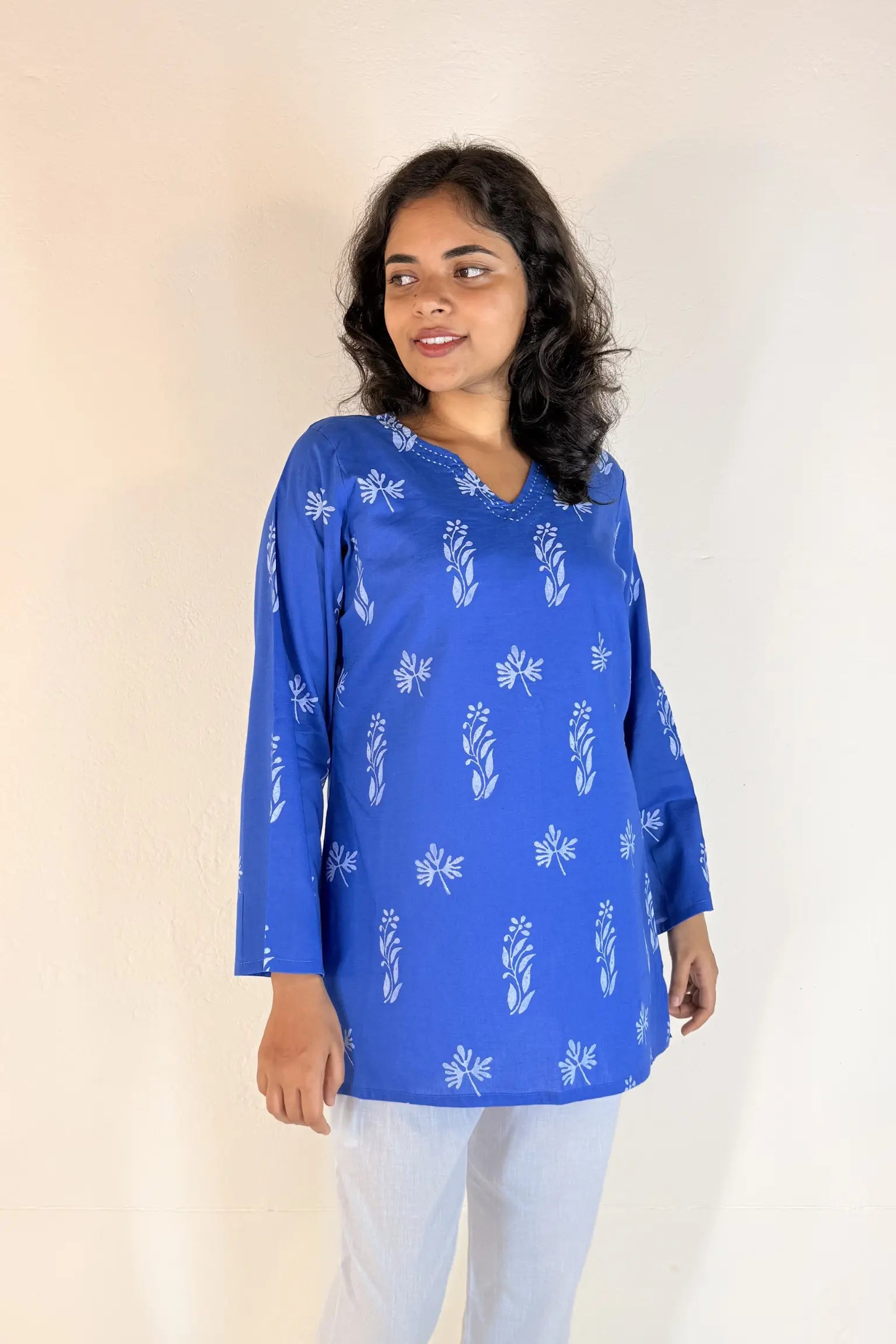 Woman wearing a blue floral patterned top against a plain background
