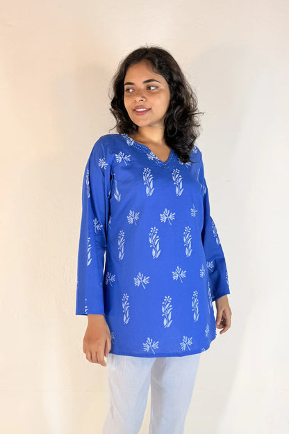 Woman wearing a blue floral patterned top against a plain background