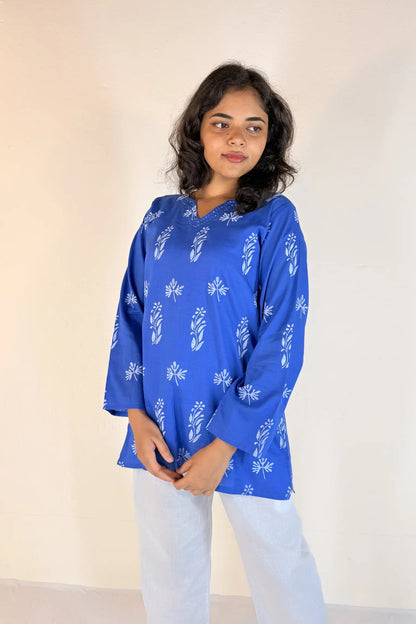 Woman wearing a blue floral patterned top against a plain background
