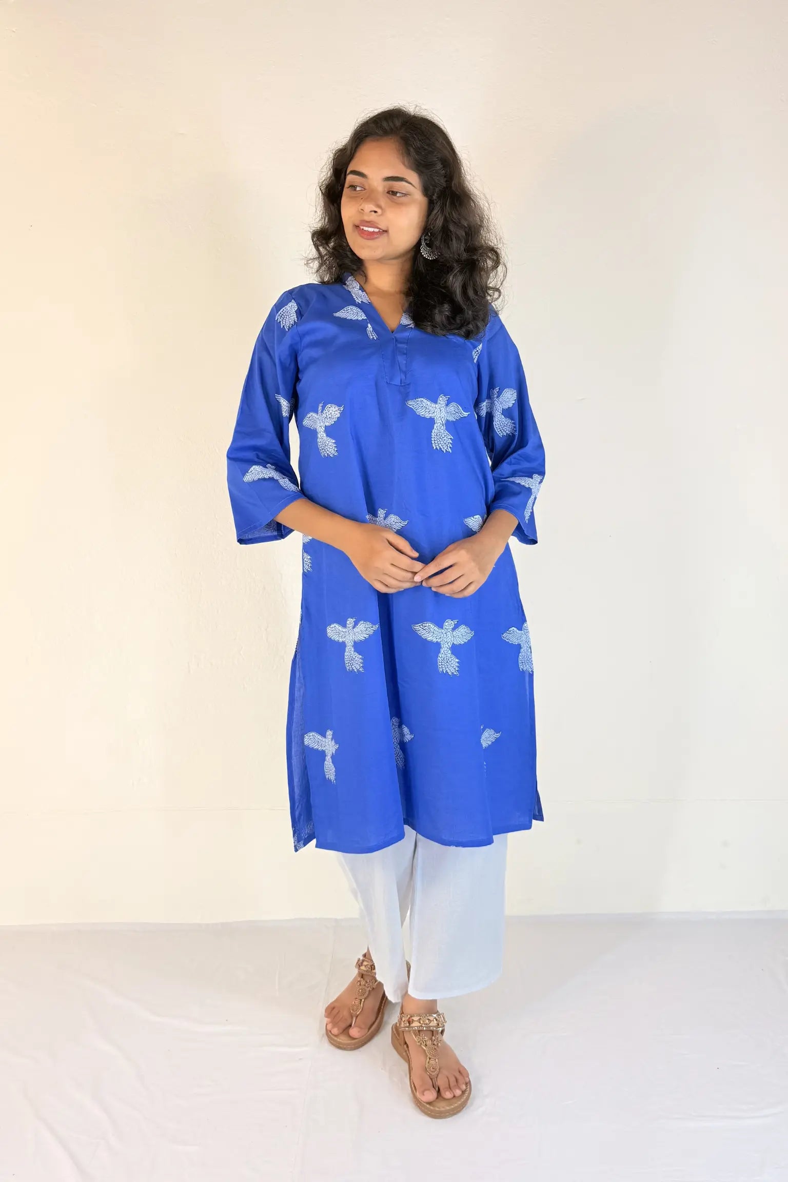 Woman wearing a pink kurta with white floral patterns on a plain background