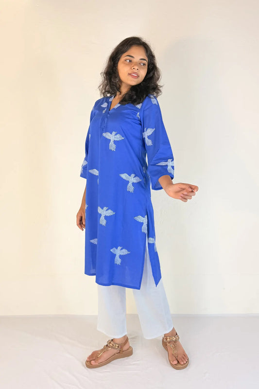 Woman wearing a blue kurta with white patterns on a plain background