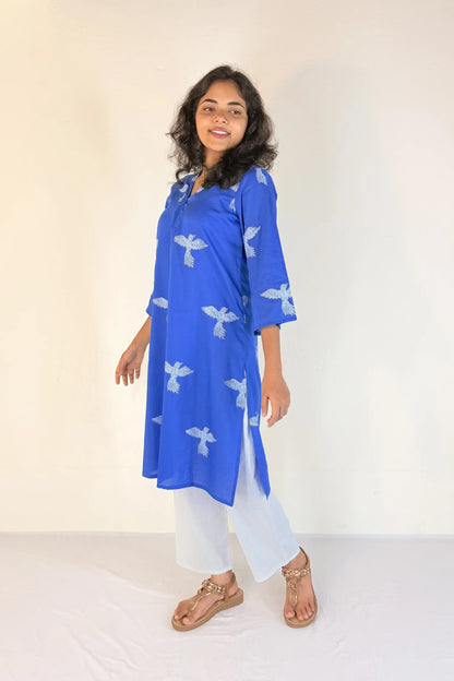 Woman wearing a blue kurta with white patterns on a plain background