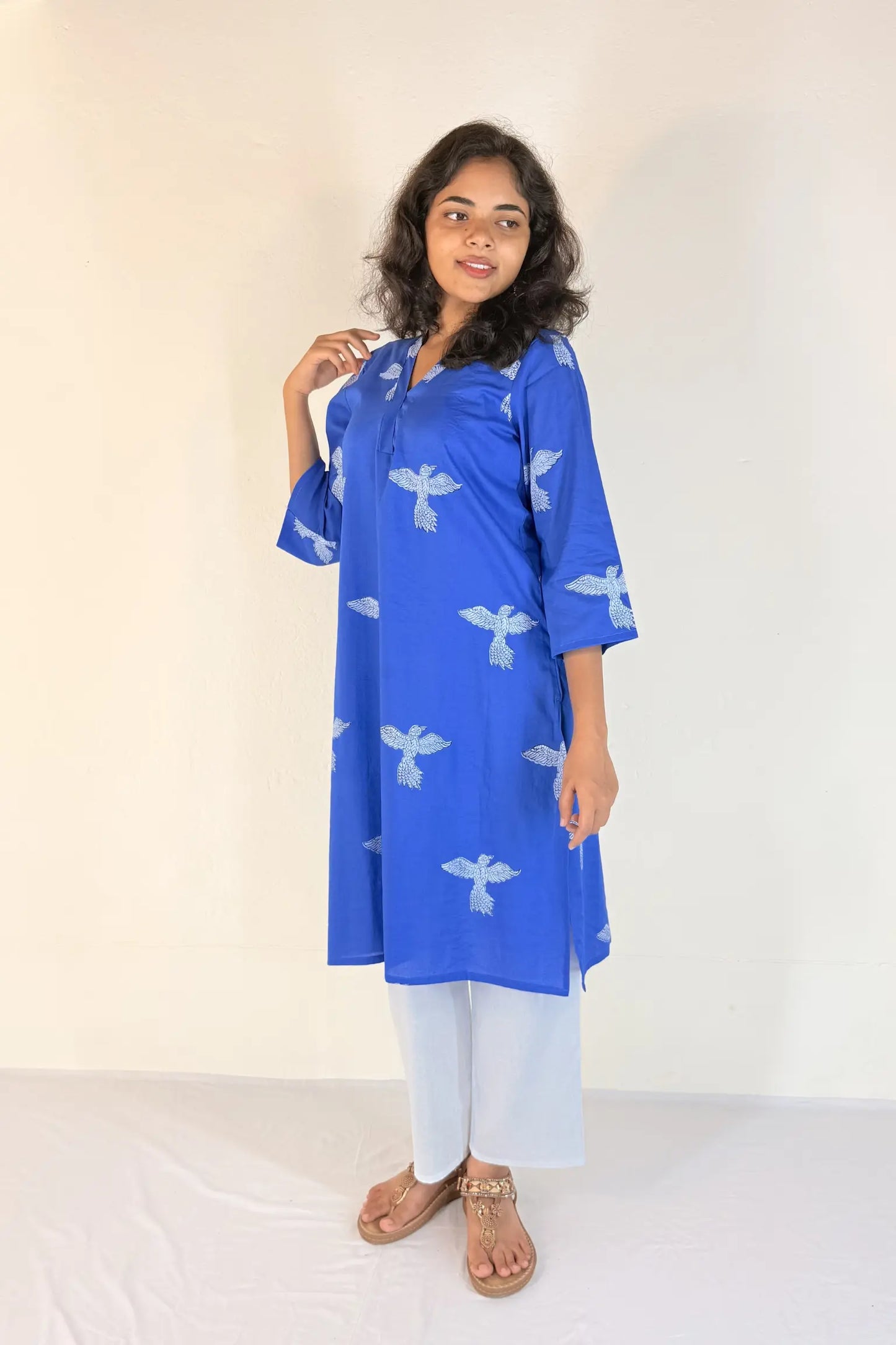 Woman wearing a blue kurta with white patterns on a plain background