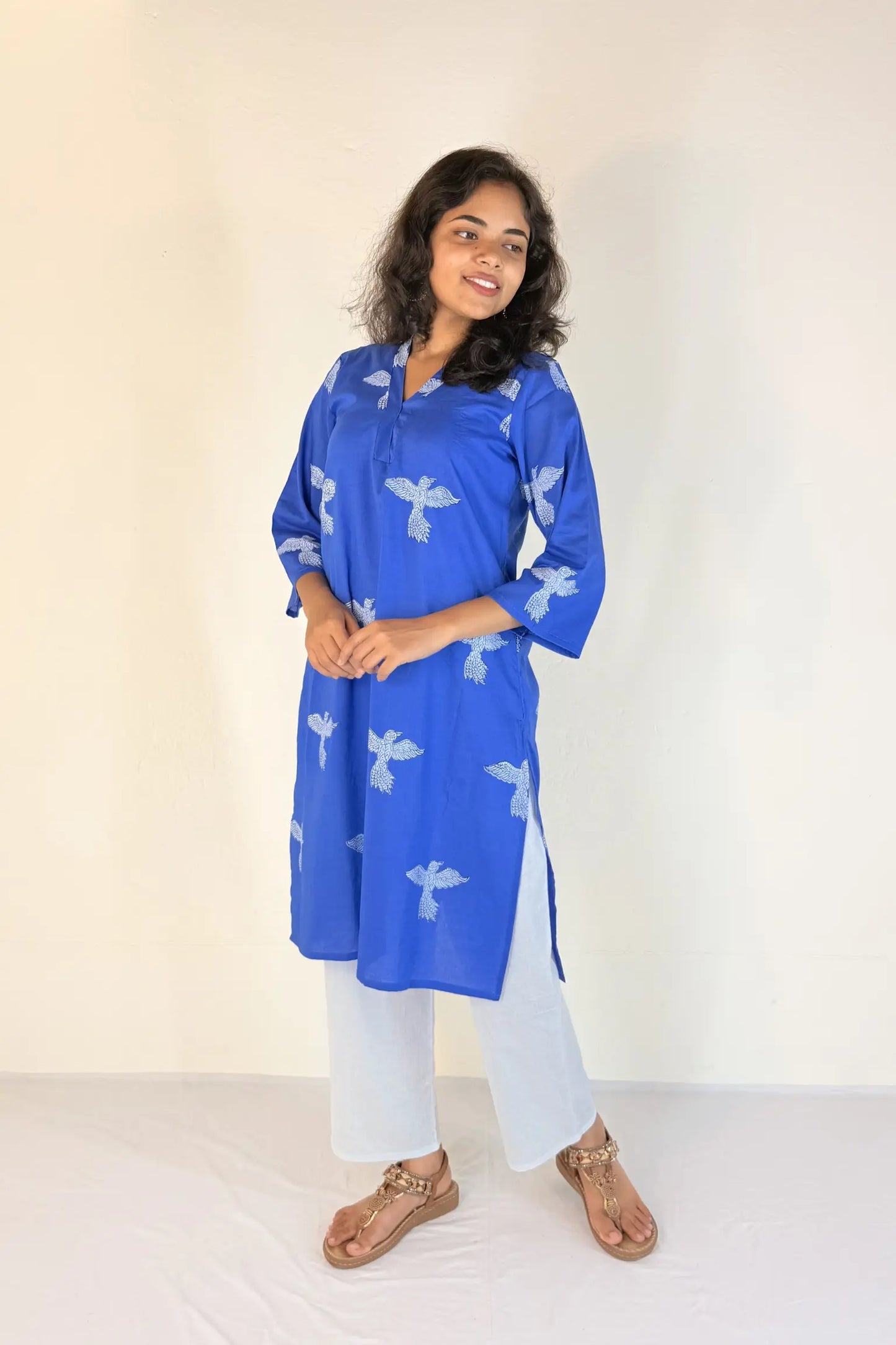 Woman wearing a blue kurta with white patterns on a plain background