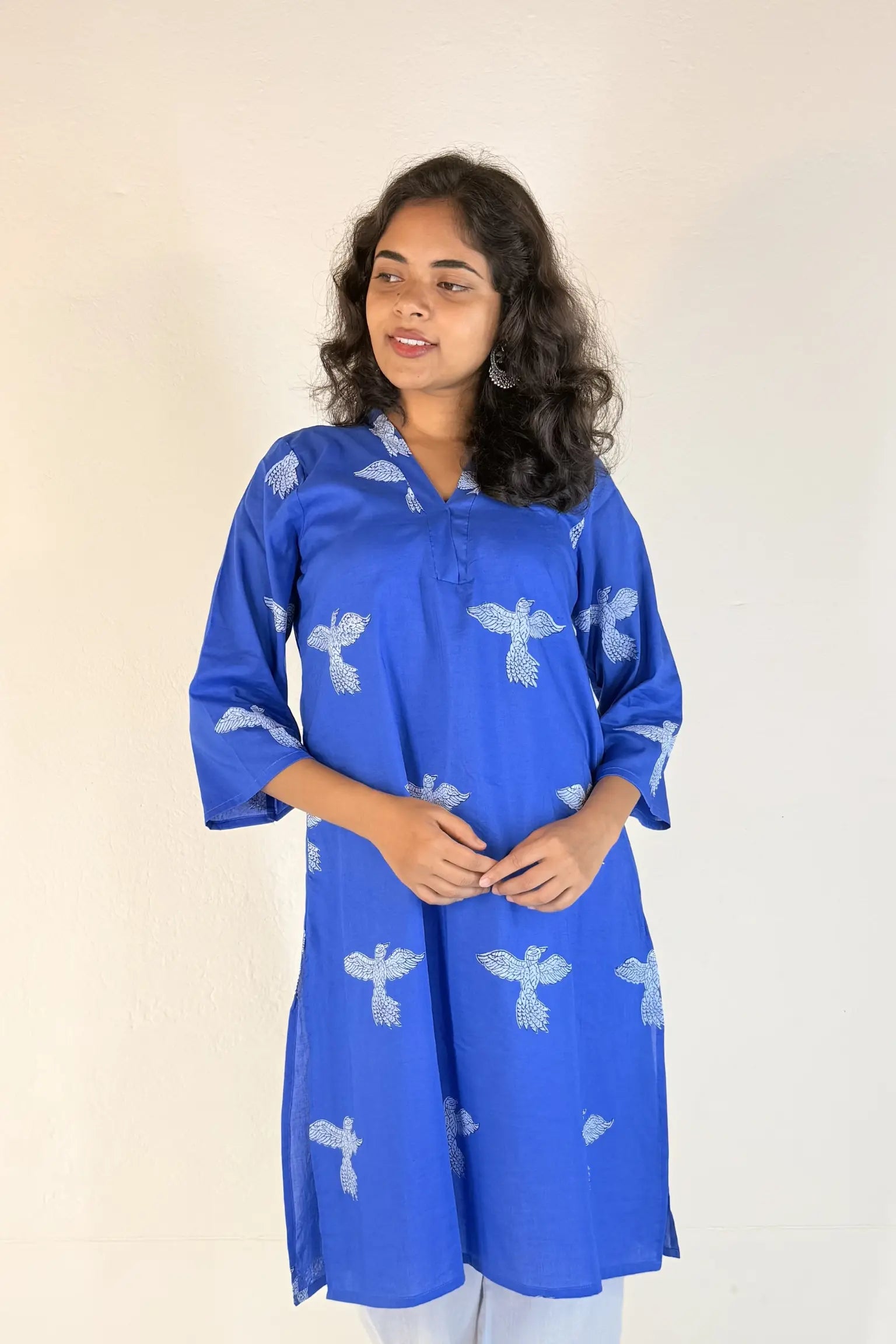 Woman wearing a blue kurta with white patterns on a plain background