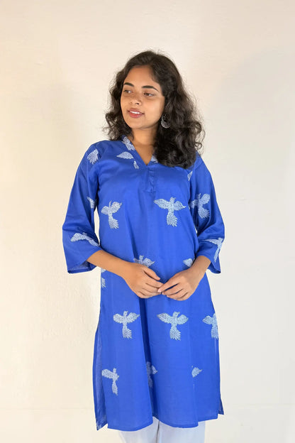 Woman wearing a blue kurta with white patterns on a plain background
