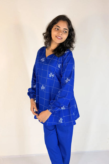 Woman wearing a blue patterned outfit against a white background