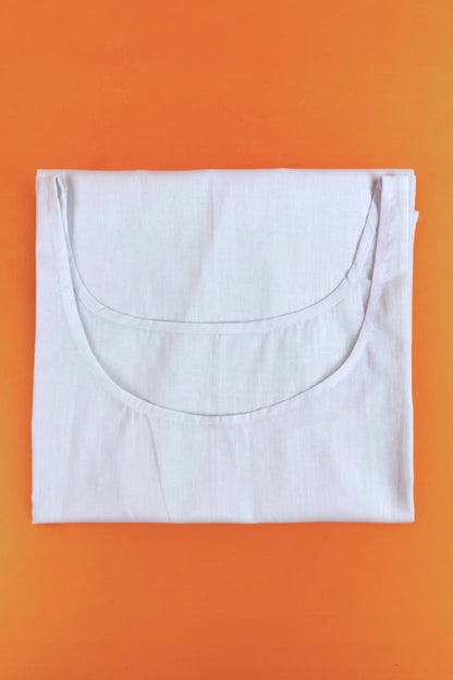 A folded white linen top with a wide scoop neckline, laid flat on a solid orange background.