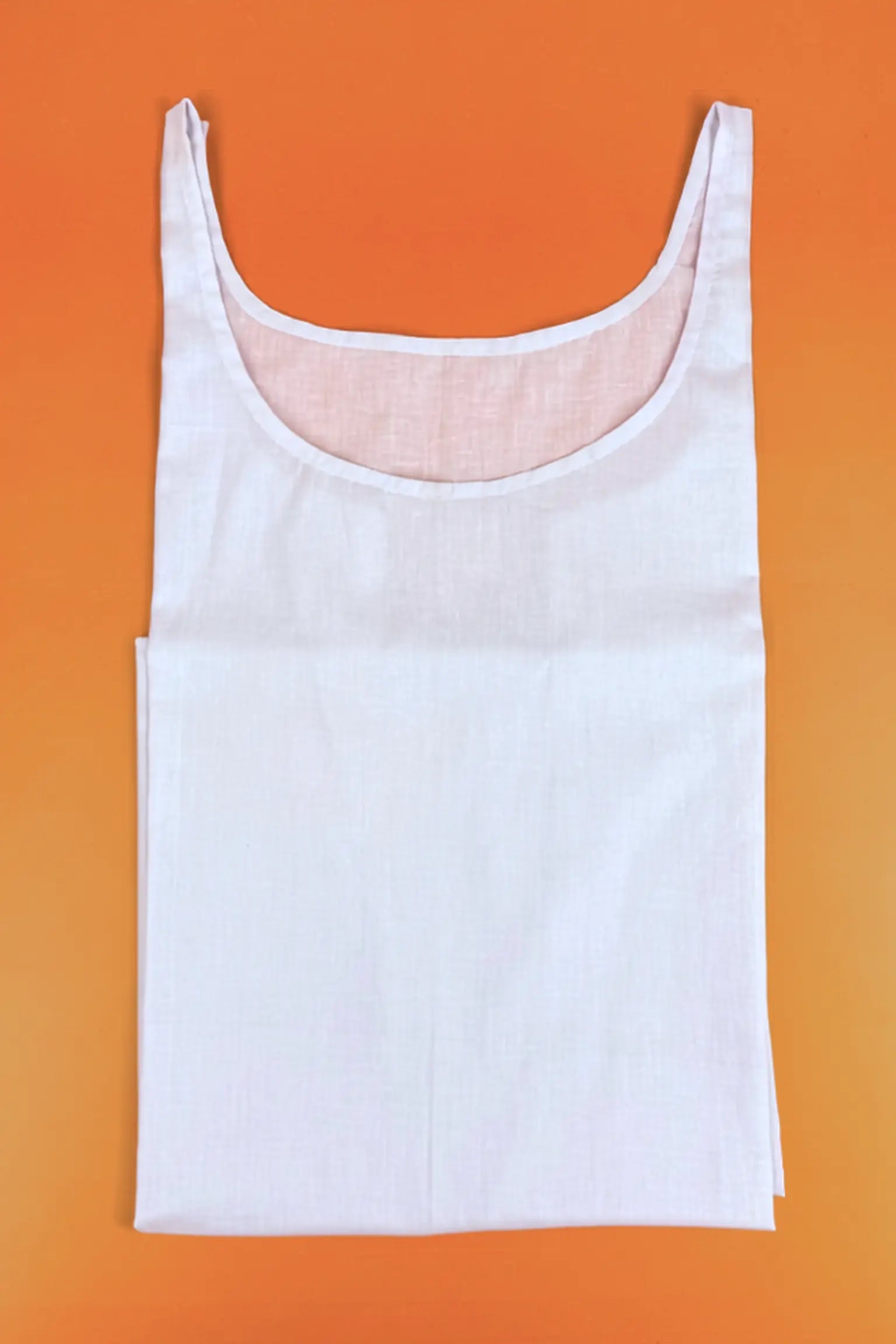 A white sleeveless tank top laid flat against a solid orange background.
