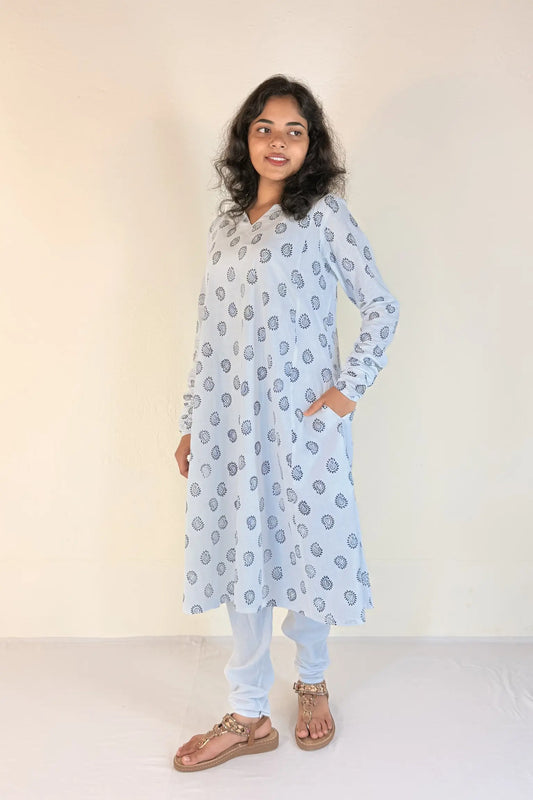 Woman wearing a light blue floral patterned kurta with white pants against a plain background