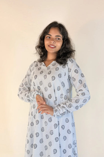 Woman wearing a light blue dress with a subtle pattern against a plain background