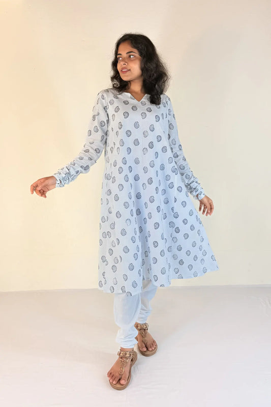 Woman wearing a blue kurta with white patterns on a plain background