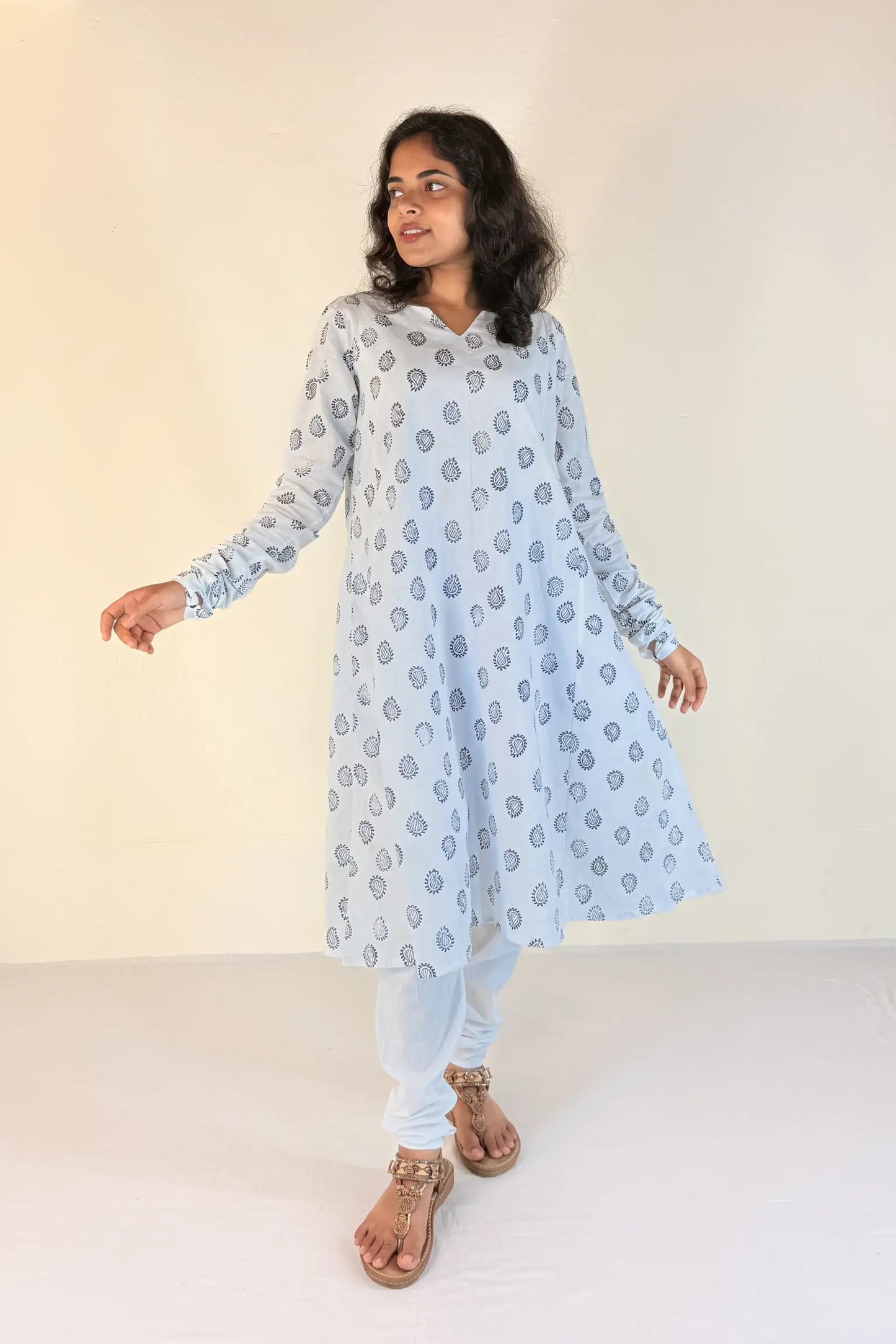 Woman wearing a blue kurta with white patterns on a plain background