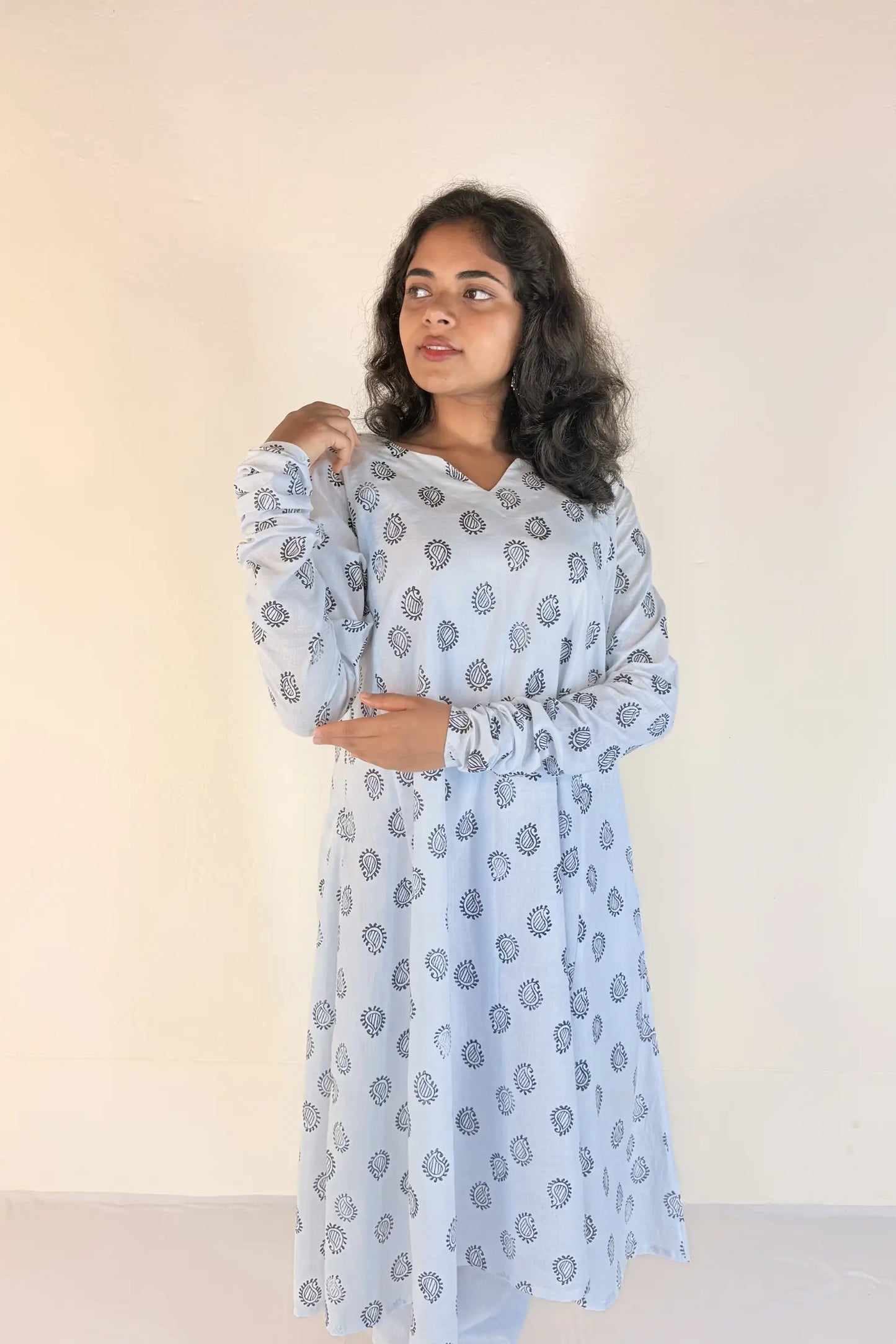 Woman wearing a light blue patterned dress against a plain background