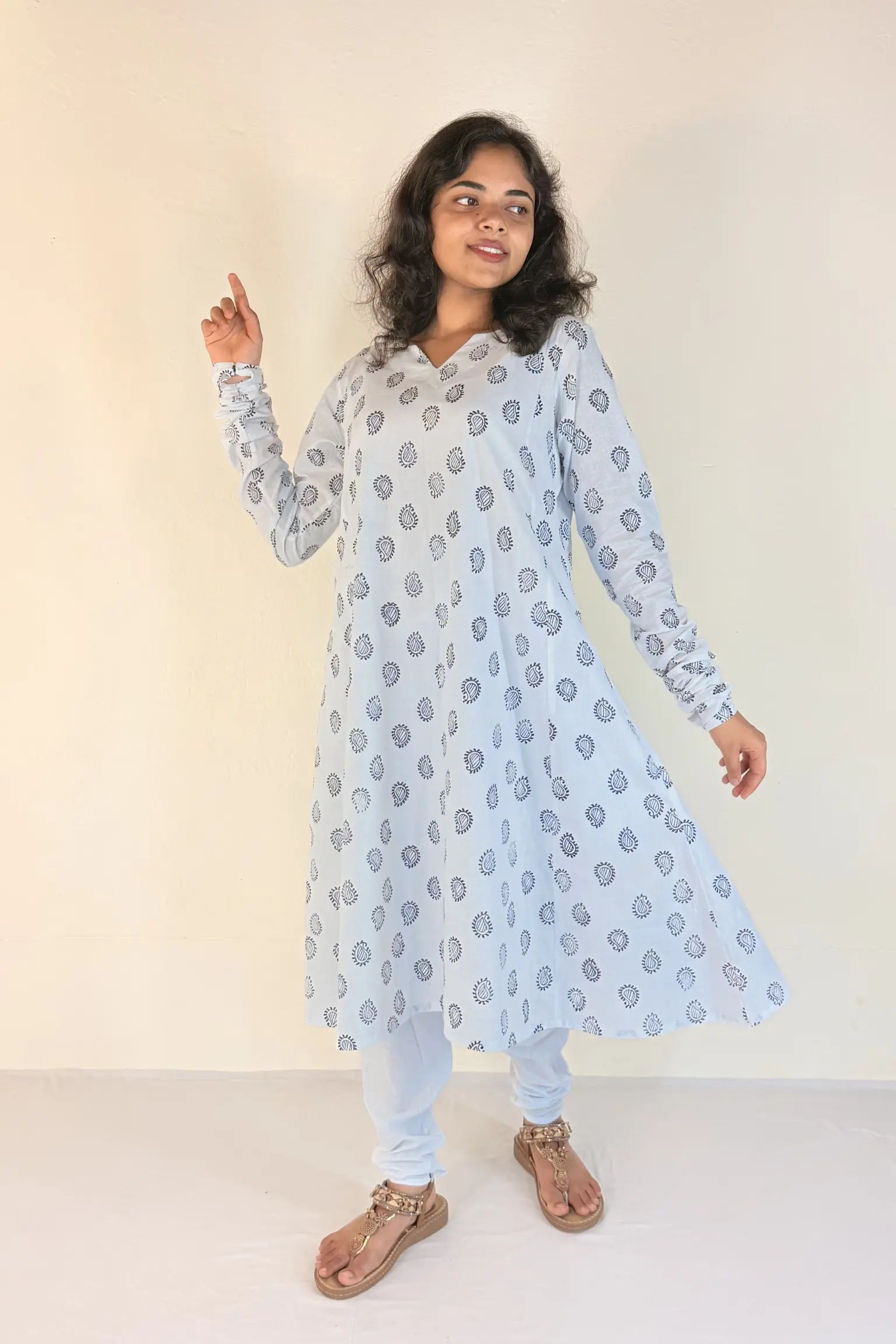 Woman wearing a light blue floral patterned kurta with white pants on a plain background