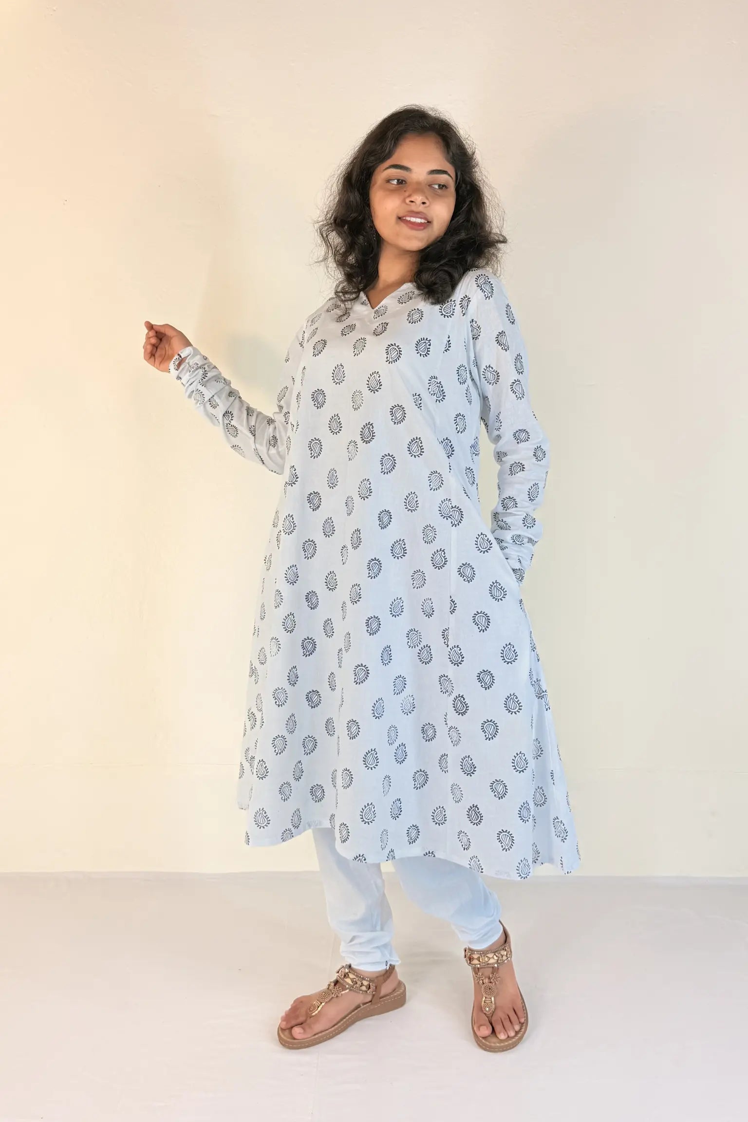 Woman wearing a light blue floral patterned kurta with white pants on a beige background