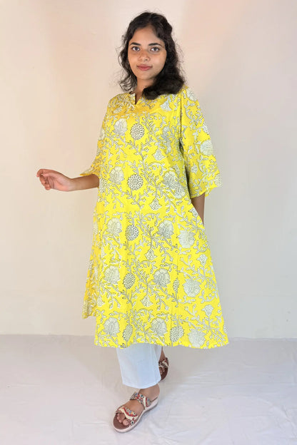 Woman wearing a yellow embroidered kurta with white pants against a plain background