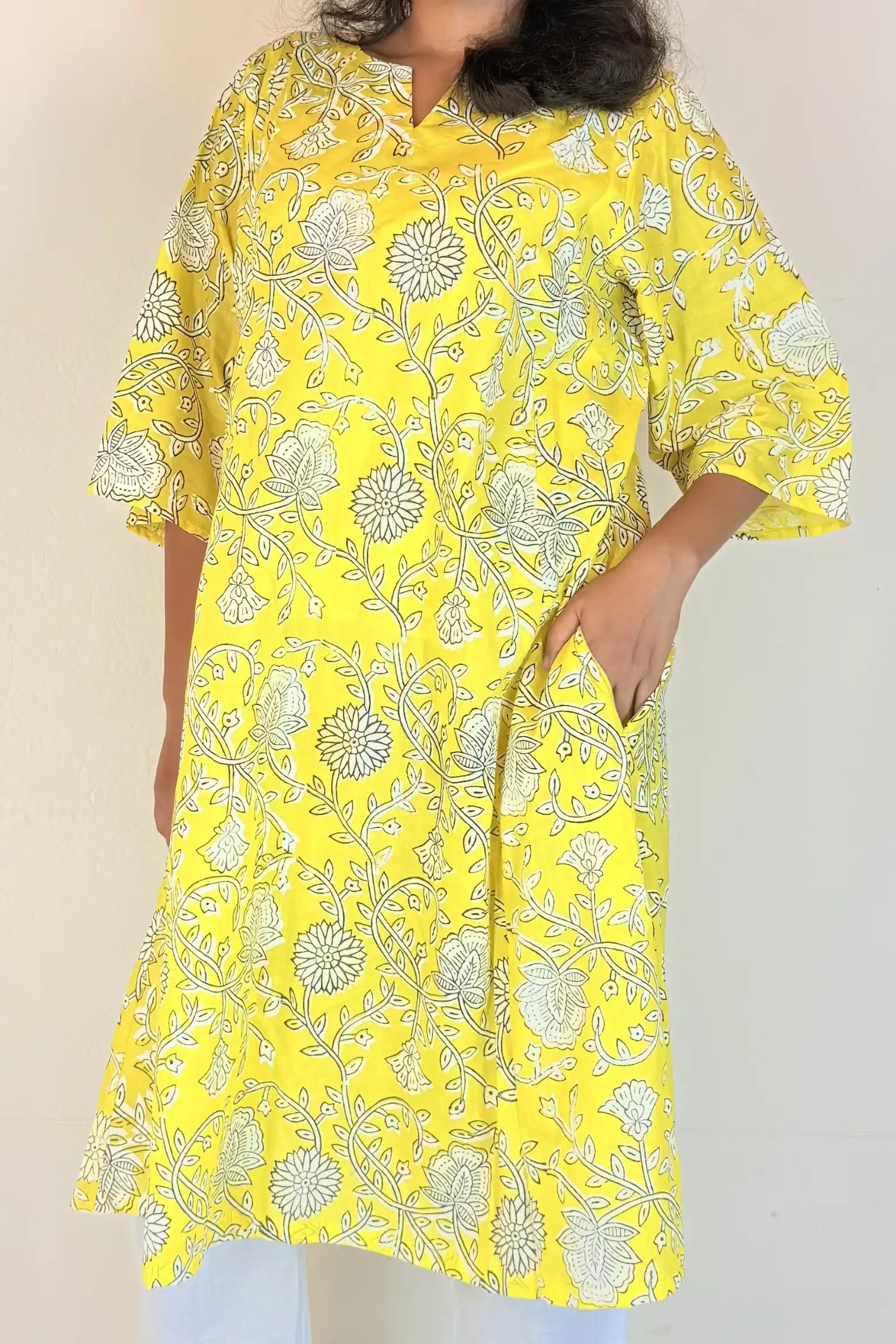 Person wearing a yellow floral dress against a plain background