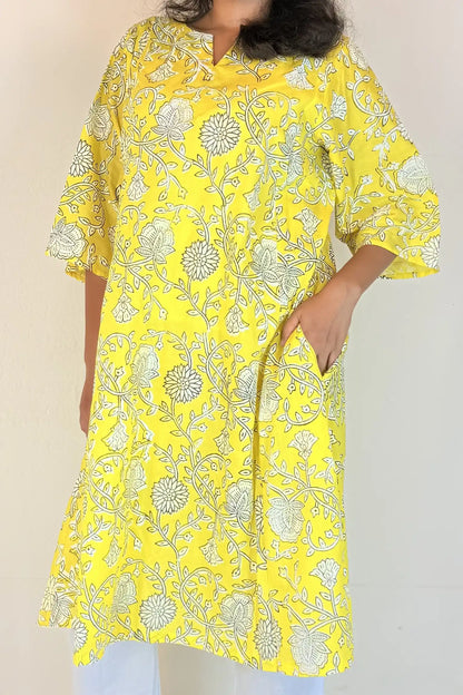 Person wearing a yellow floral dress against a plain background
