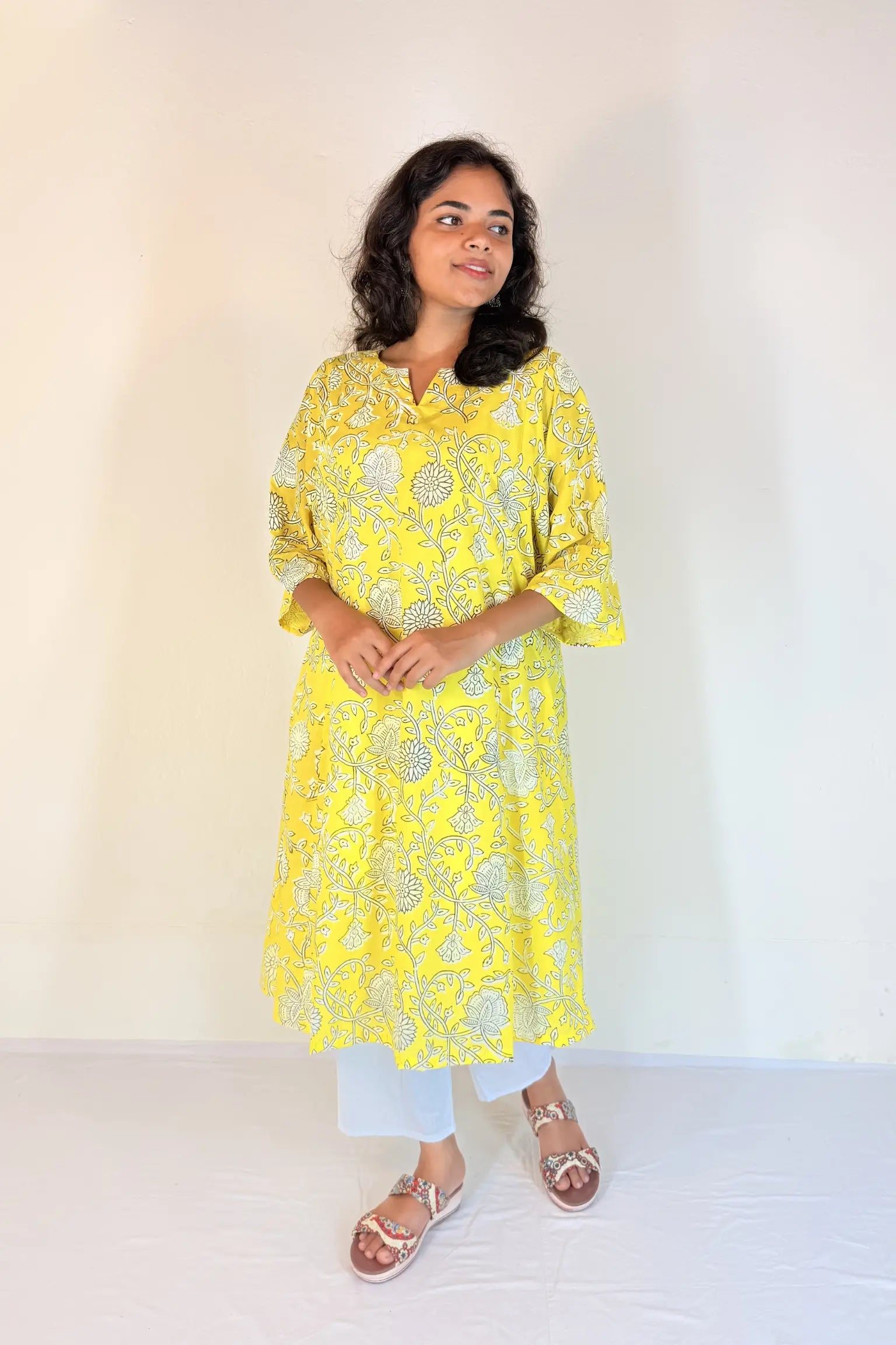 Woman wearing a yellow floral dress against a white background