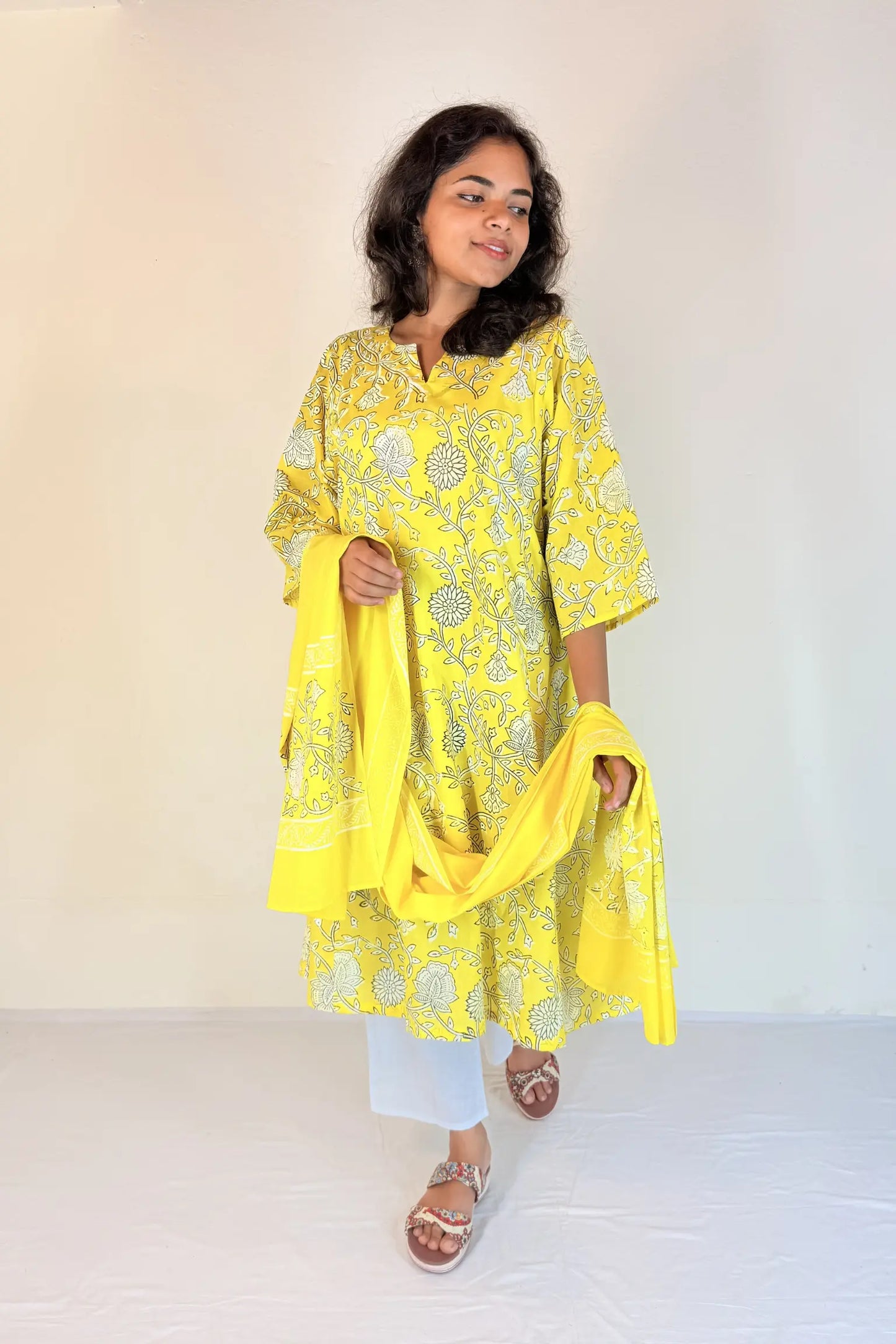 Woman wearing a yellow embroidered kurta with a matching dupatta against a white background
