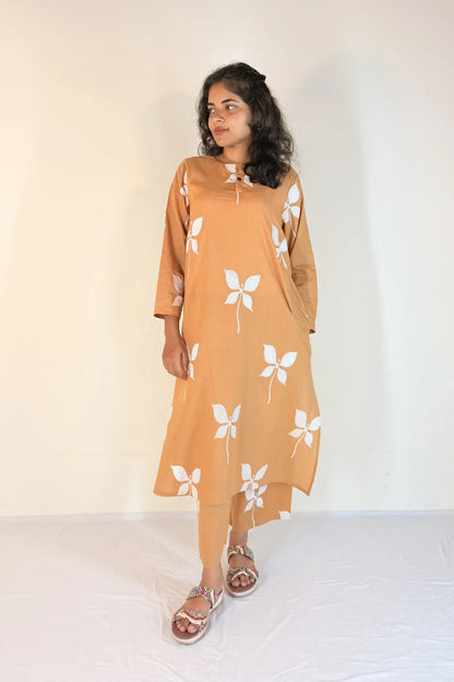 Woman wearing a mustard yellow dress with white floral patterns on a white background