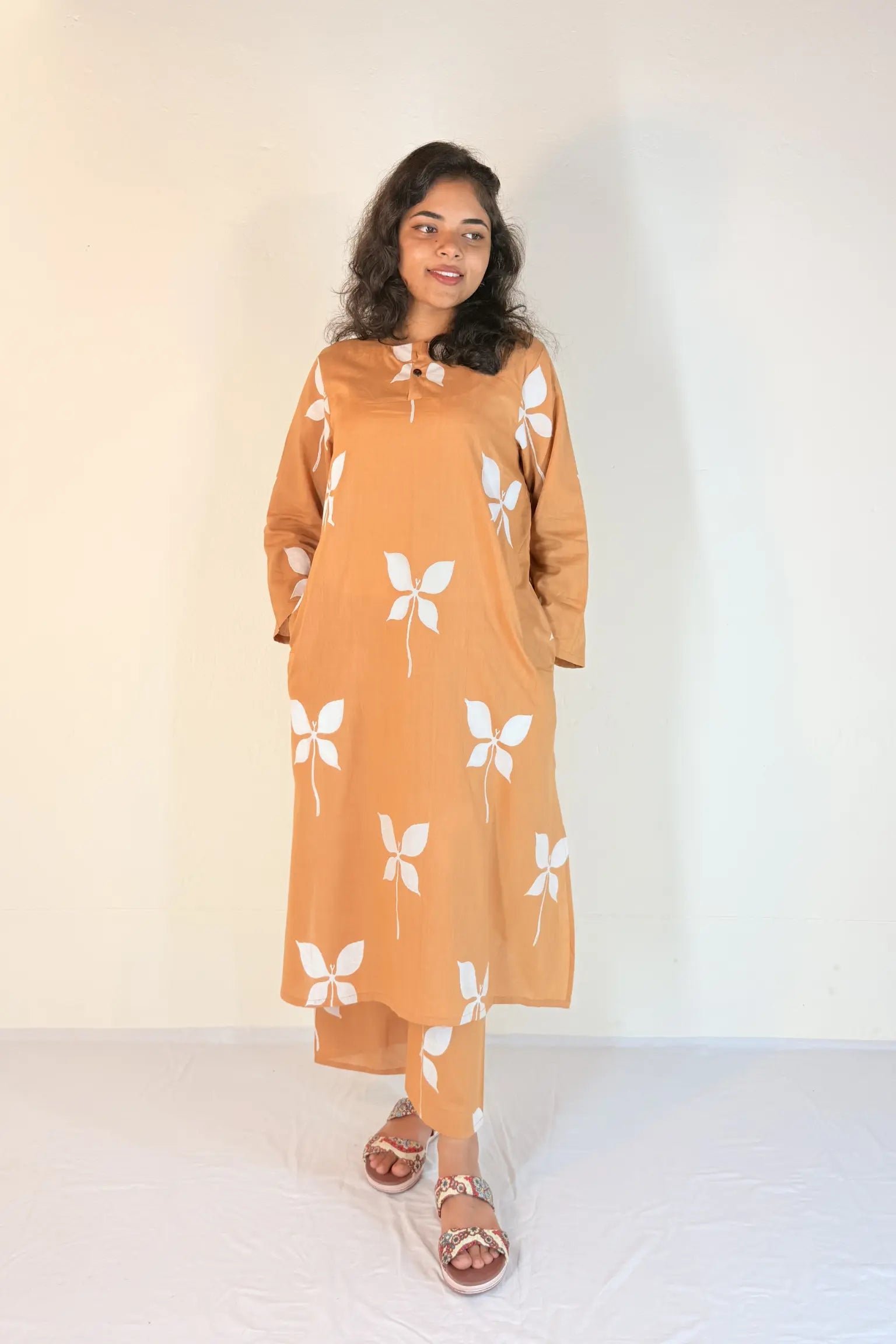 Woman wearing a mustard yellow dress with white butterfly patterns on a plain background