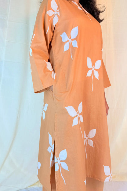 Person wearing an orange kimono with white floral patterns against a light background