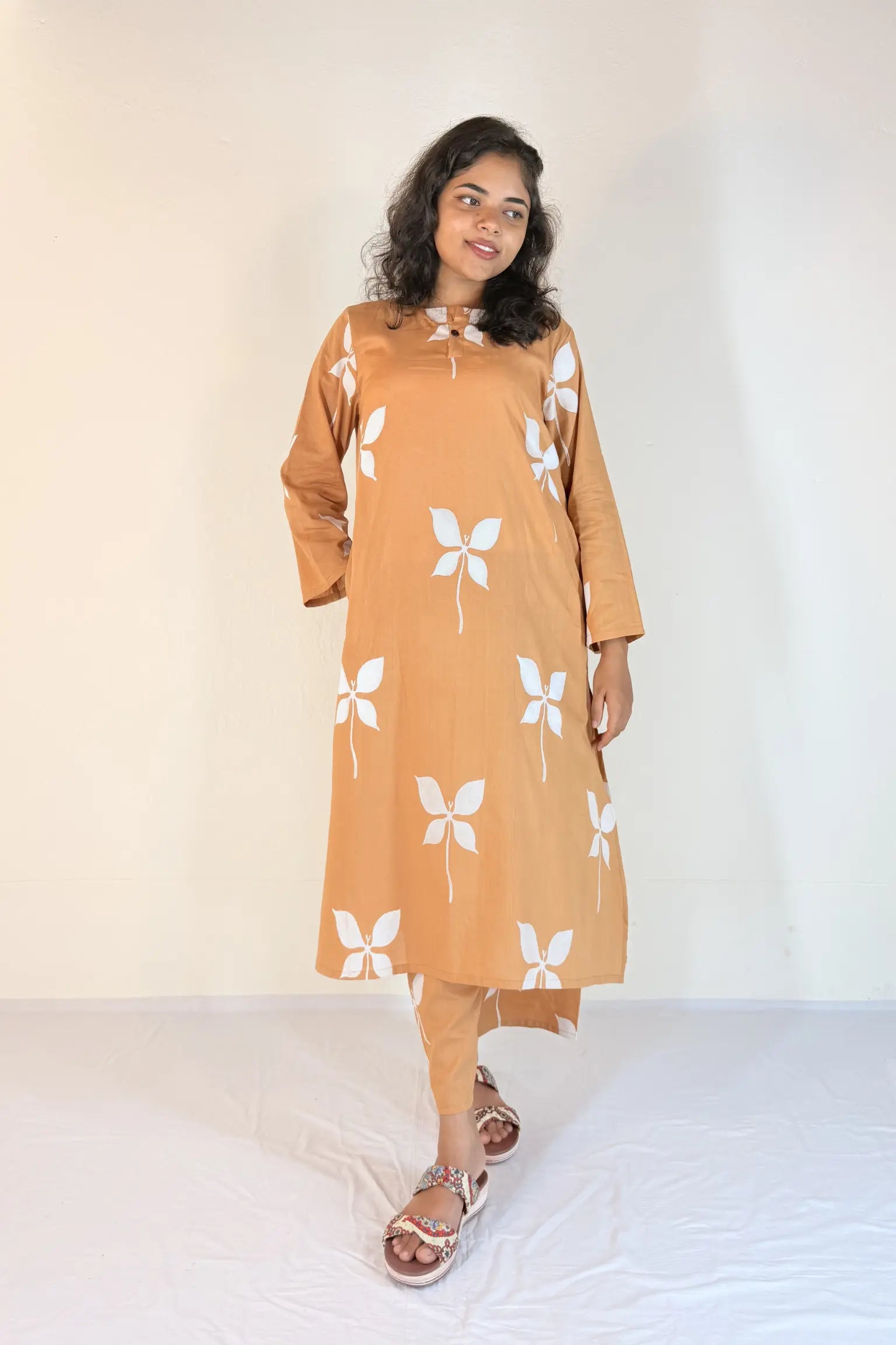 Woman wearing a mustard yellow kurta with white butterfly patterns on a plain background