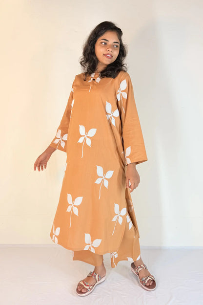 Woman wearing a mustard yellow dress with white floral patterns on a plain background