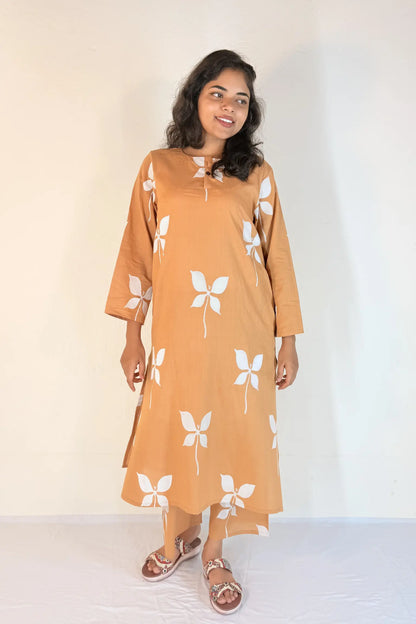 Woman wearing a mustard yellow dress with white floral patterns on a plain background