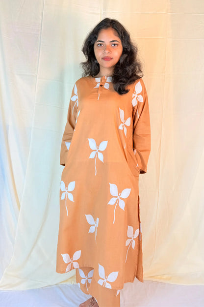 Woman wearing an orange dress with white floral patterns against a light background