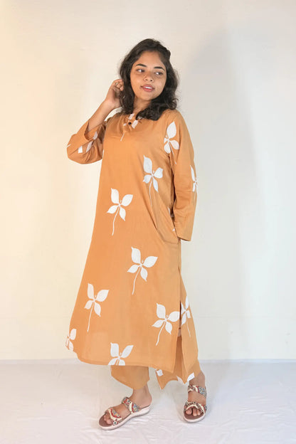 Woman wearing a mustard yellow dress with white floral patterns against a plain background