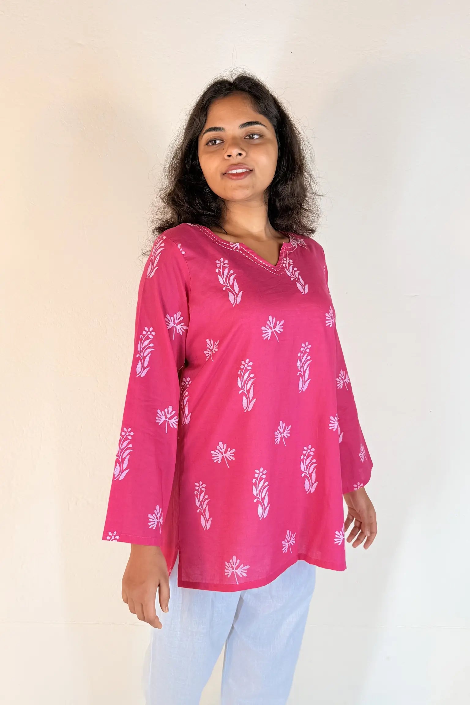 Woman wearing a pink floral blouse against a plain background
