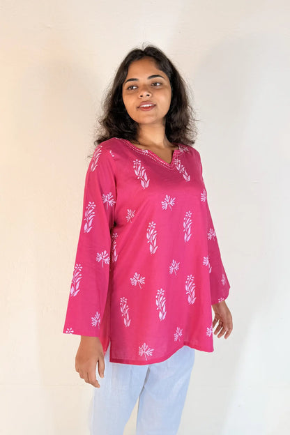 Woman wearing a pink floral blouse against a plain background