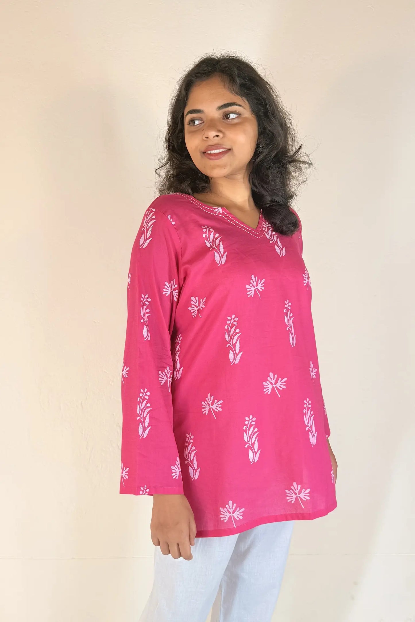 Woman wearing a pink patterned top against a plain background