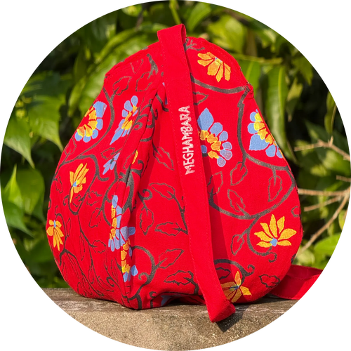 Red fabric pouch with floral patterns and 'MEGHAMBARA' branding on a natural background