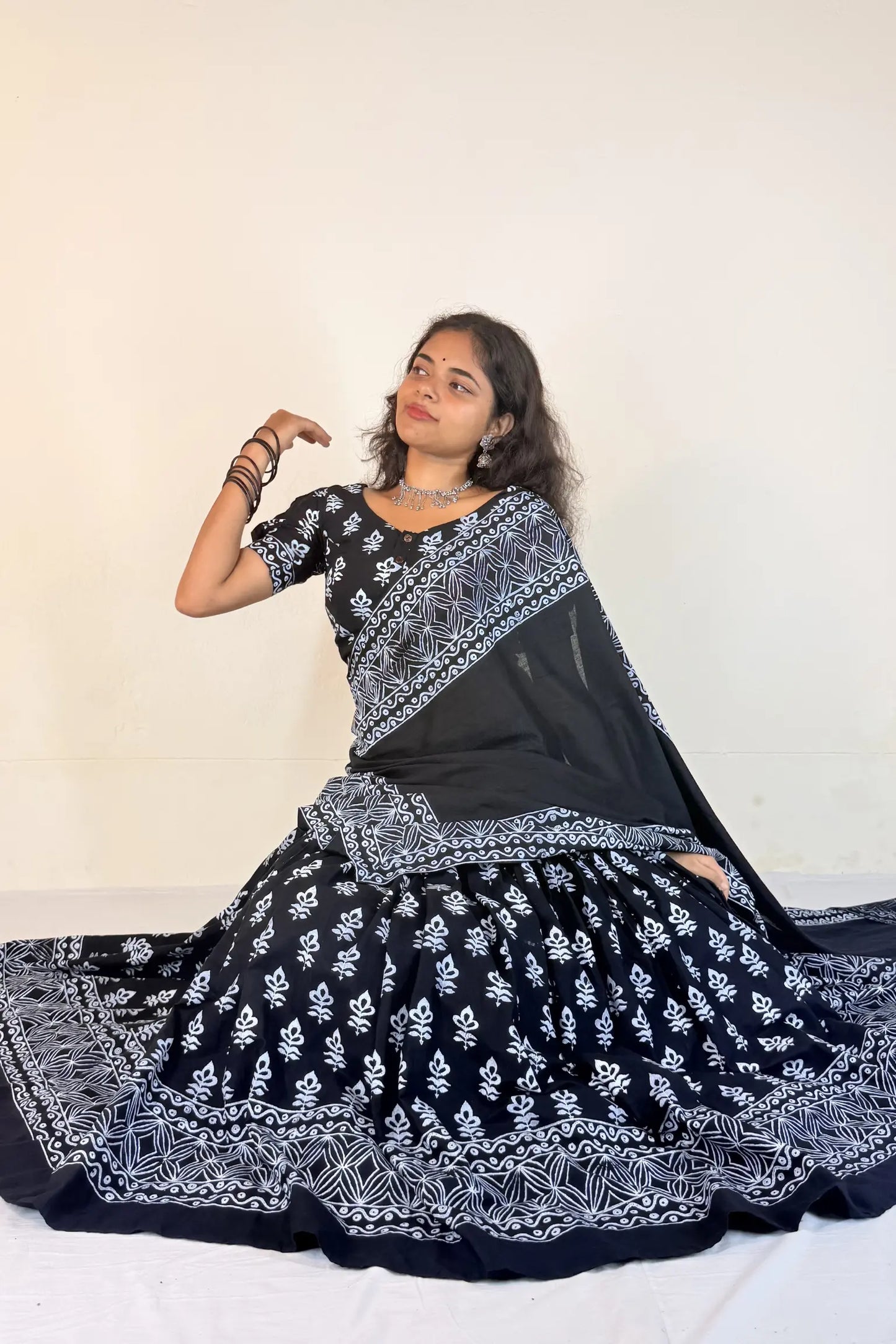 Woman wearing a colorful traditional outfit with a black and white gopi dress on a white background