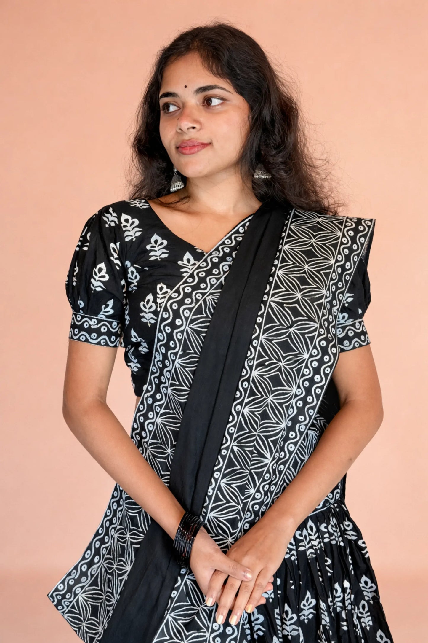 Side angle portrait of model wearing Kalindi black and white block print cotton gopi dress, showcasing blouse and border detailing