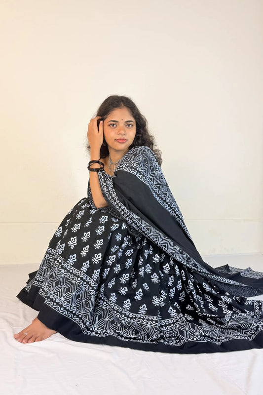 Woman wearing a black and white patterned Gopi Dress sitting on a bed.