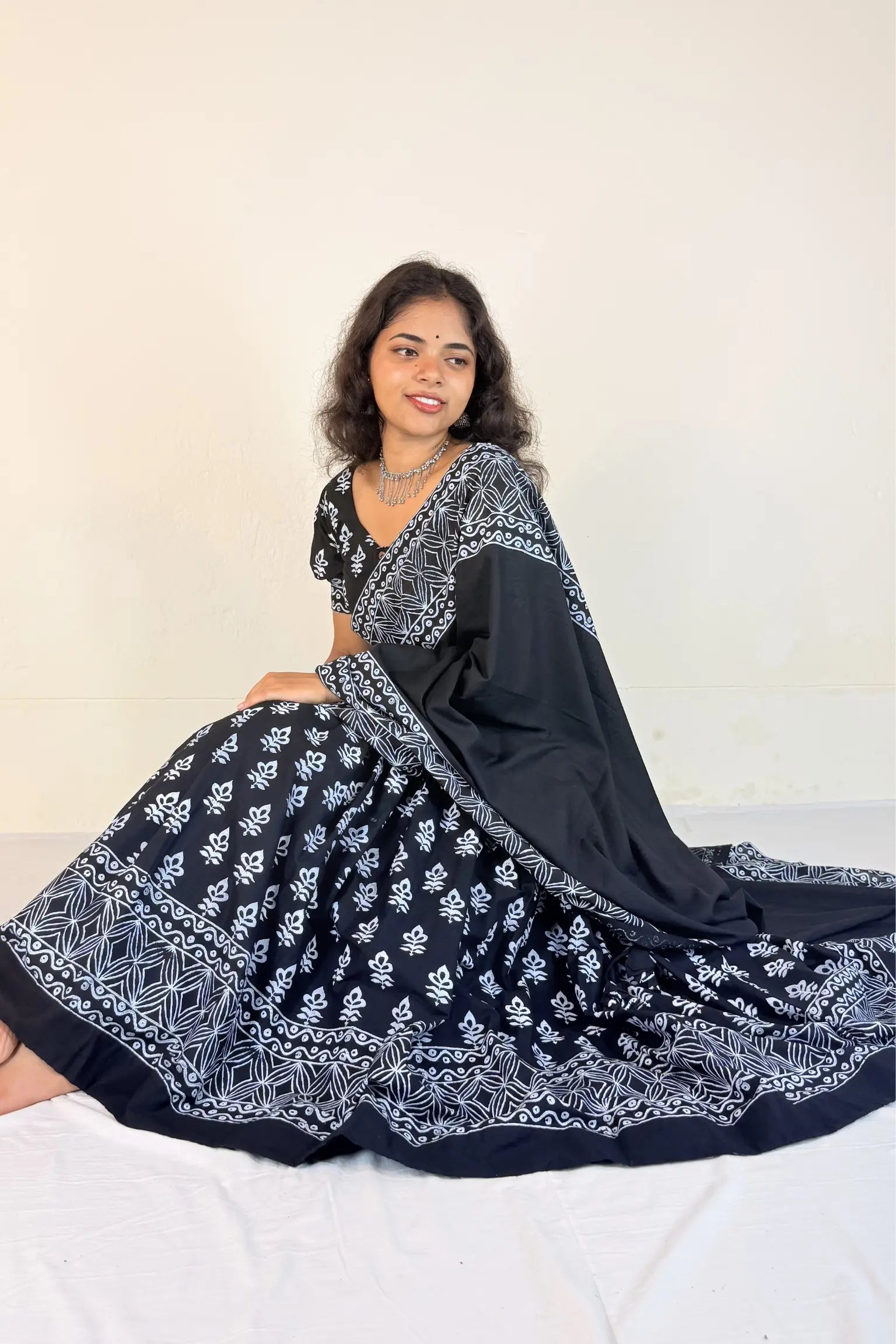 Woman wearing a colorful traditional outfit with a black blouse and black gopi dress against a white background
