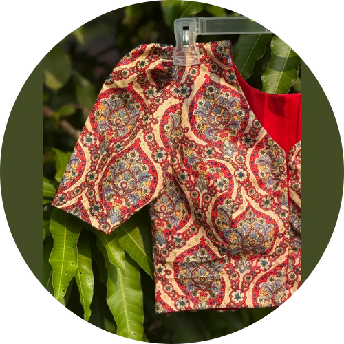 Patterned fabric blouse with red and beige design on a green leaf background